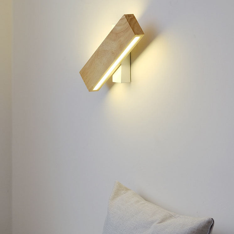 Wooden bar light turned at a diagonal on a white wall, glowing warmly above a cream cushion. 1