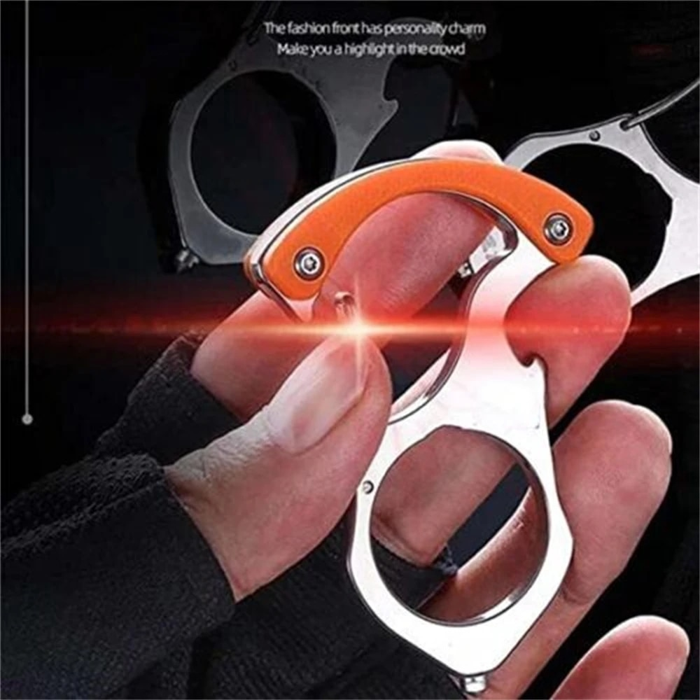 Close-up of a gloved hand gripping the steel carabiner keyring with orange handle, finger through the large ring, on a dark background. 1