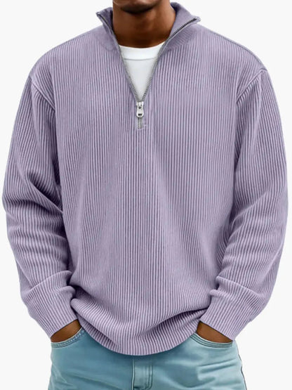 Man wearing the ribbed quarter-zip jumper in lilac purple over a white tee, hands in the pockets of light blue jeans. 9