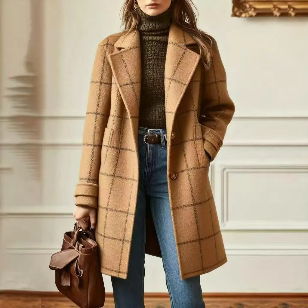 Model in a panelled room wears the camel coloured checked coat with dark check lines and a brown bag 10