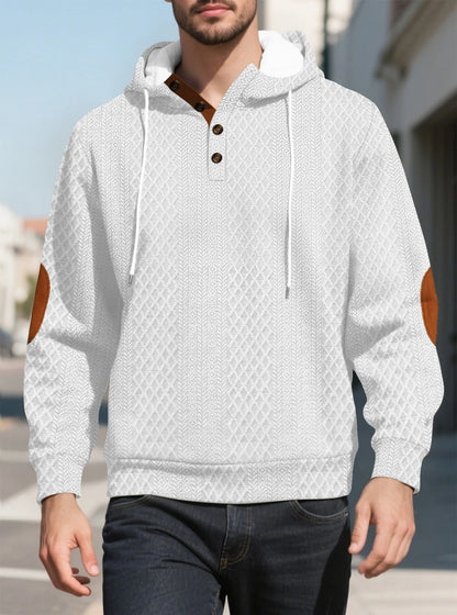 Model walking outdoors in a white diamond-textured hoodie, front view with tan elbow patches and button placket 10