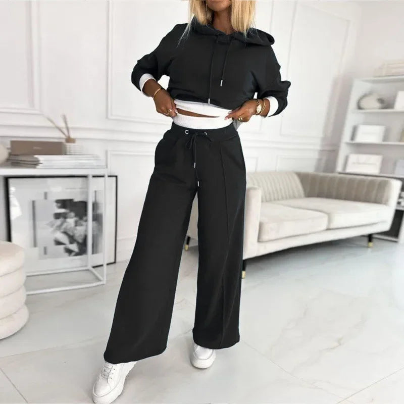 Model in the black set lifting the hoodie hem to reveal the white waistband and drawstring 10