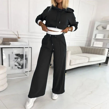 Model in the black set lifting the hoodie hem to reveal the white waistband and drawstring 10