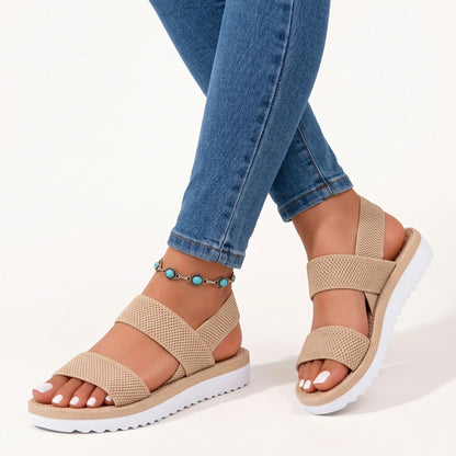 Beige woven-strap sandals worn with blue jeans and a turquoise anklet on a plain white background 10