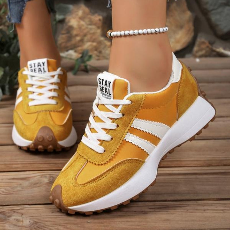Mustard yellow suede trainers with white stripes and white laces, worn on wooden boards with a bead anklet 6