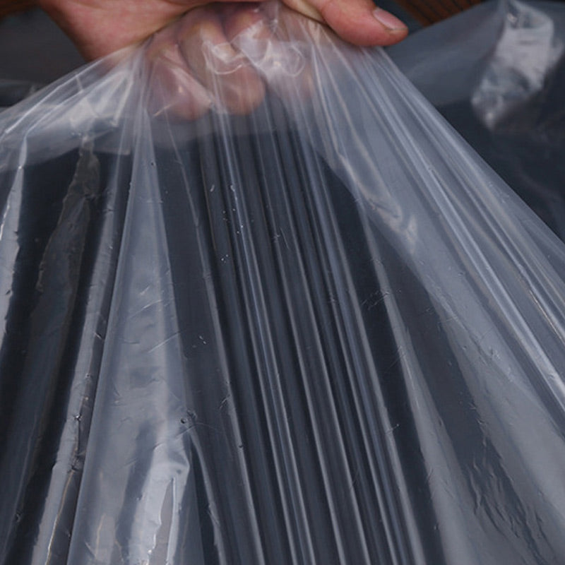 Hand holding up the clear plastic sheet in soft folds, showing how thin and see-through the material is. 6