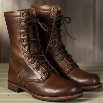 Pair of brown leather lace-up boots with dark laces and metal eyelets, shown from the front on a wooden surface. 1
