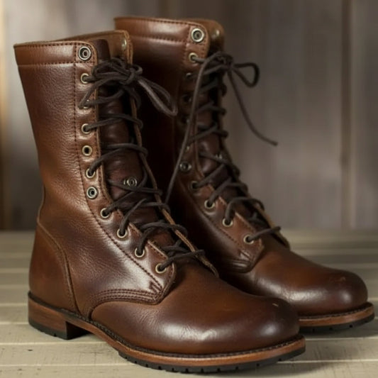 Pair of brown leather lace-up boots with dark laces and metal eyelets, shown from the front on a wooden surface. 1