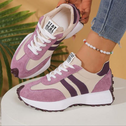 Pink and cream trainers with dark purple stripes, worn with rolled jeans while one shoe is lifted 11