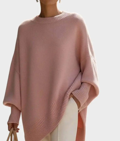 Pink jumper held in close view with ribbed neck and cuffs, worn over white trousers with a beige bag 11