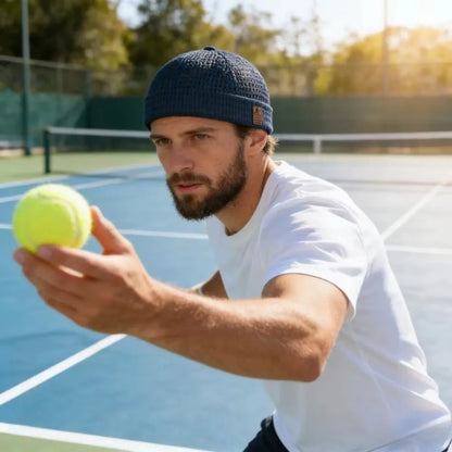 Bearded man on a tennis court wearing the navy cap while holding a tennis ball 11