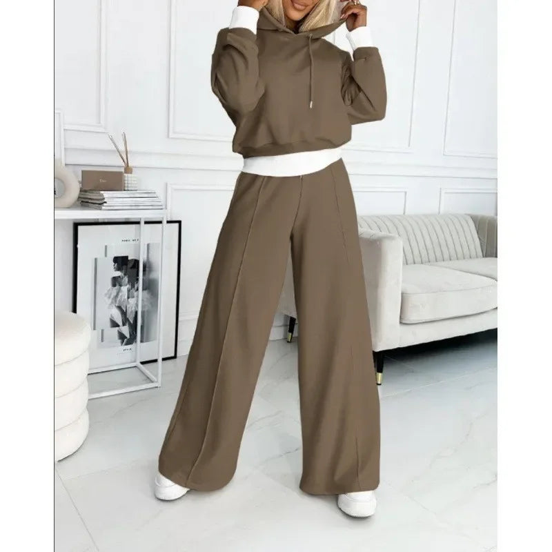 Brown hooded set with white cuffs and waistband, model touching the hood in a white room 11