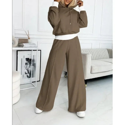 Brown hooded set with white cuffs and waistband, model touching the hood in a white room 11