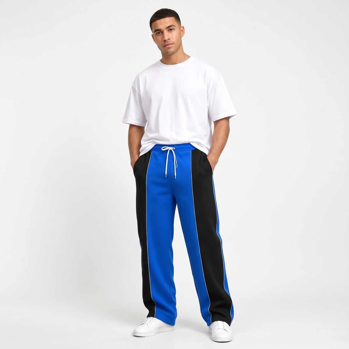 Studio shot of a model in blue sweatpants with black side panels and thin white piping 11