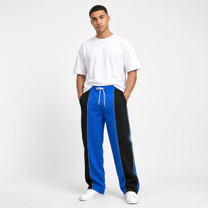 Studio shot of a model in blue sweatpants with black side panels and thin white piping 11