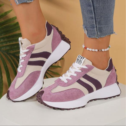 Side view of pink suede trainers with cream panels and purple stripes, worn on a white stand 12