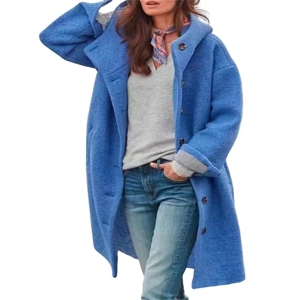 Blue coat with a hood worn over a grey top and scarf, on a plain white background 12