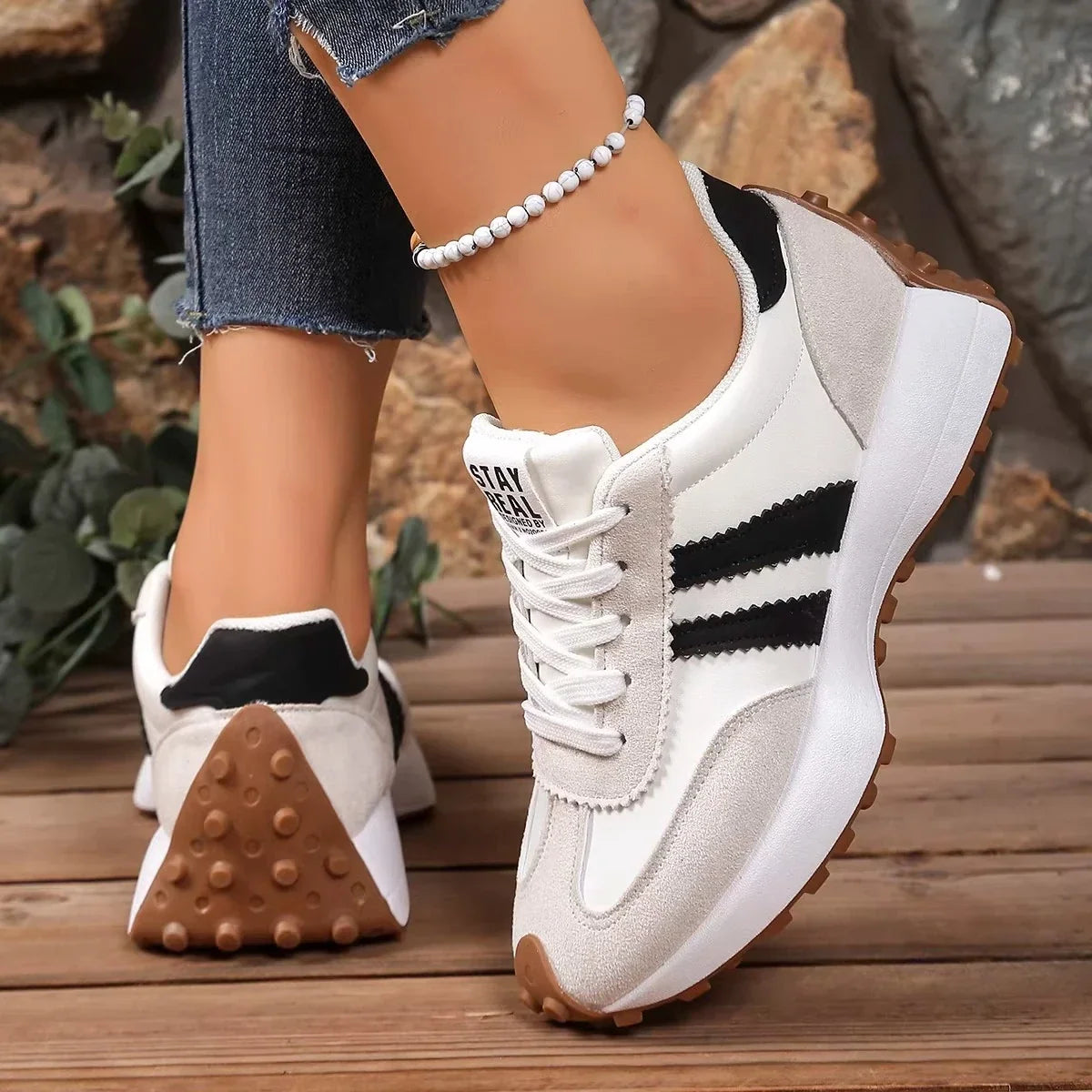 Cream trainers with black stripes, showing the studded gum-coloured heel on one shoe and the side of the other 12