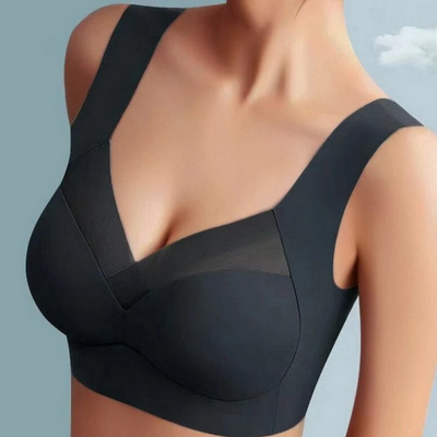 Model wearing the seamless bra in black, front view showing the smooth cups, wide straps and sheer mesh neckline panel. 16