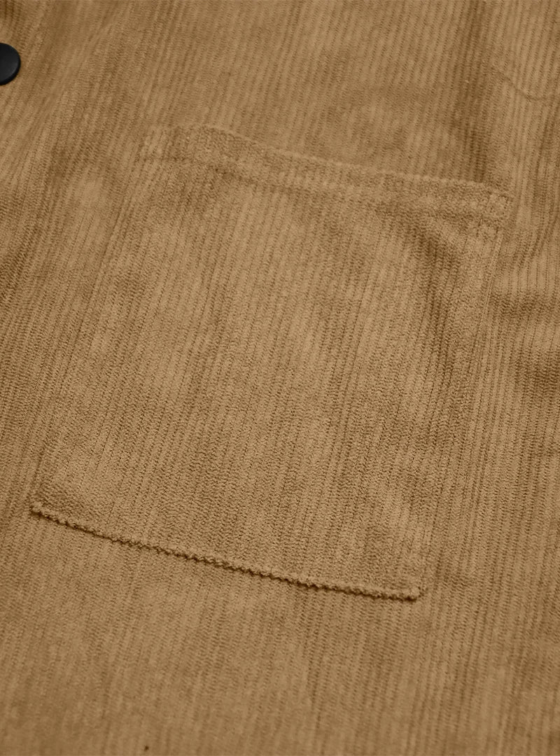 Close-up of a patch chest pocket on the tan ribbed shirt beside a black button 12