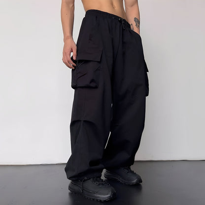 Model wears the baggy cargo trousers in black with black chunky trainers, side view 3