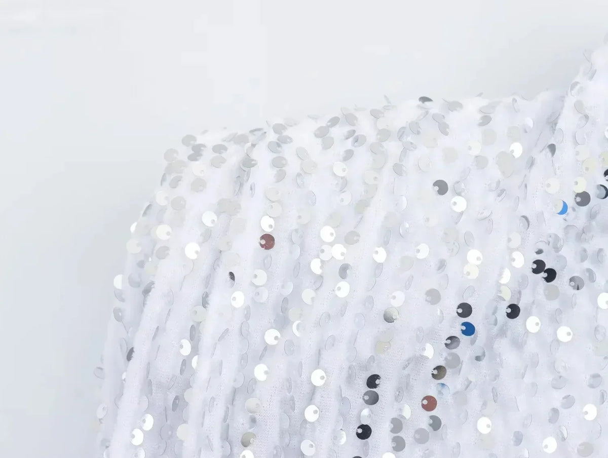 Close-up of the white dress's shoulder, showing silver sequins on soft textured fabric 13