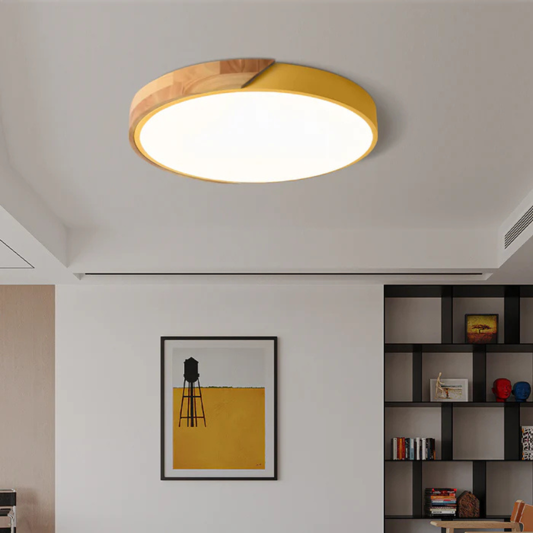 Yellow and wood round ceiling light in a living room with a framed print and black shelving 4