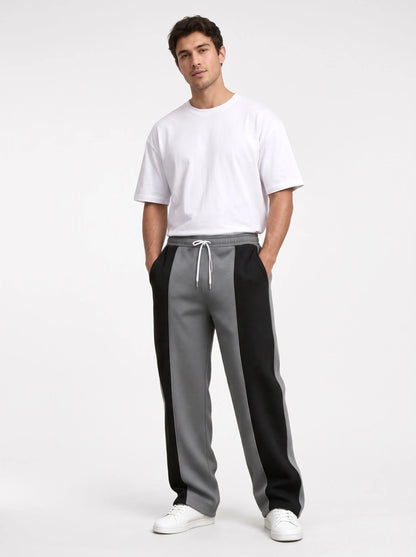 Studio shot of a model in grey sweatpants with black side panels and a white tee 13