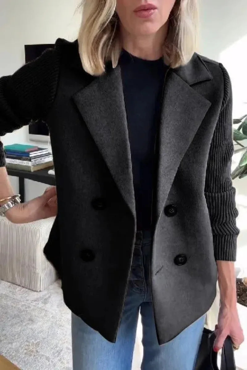Close-up of black double-breasted jacket on model, showing lapels and ribbed knit sleeves 13
