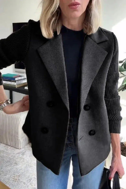 Close-up of black double-breasted jacket on model, showing lapels and ribbed knit sleeves 13