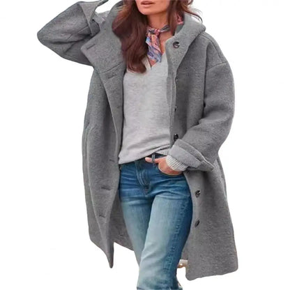 Grey coat with a hood worn open over a grey top and scarf, on a plain white background 13