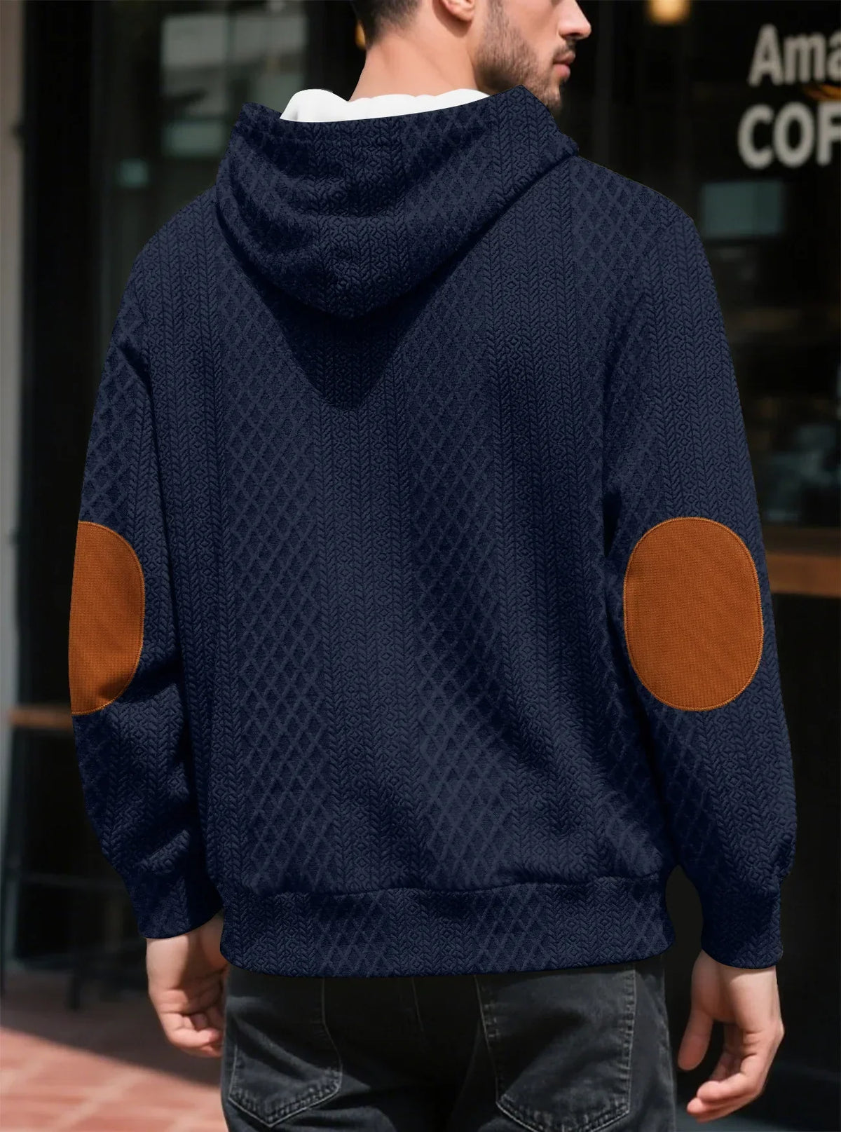 Back view of a navy textured hoodie worn outdoors, showing large tan elbow patches and ribbed hem 14