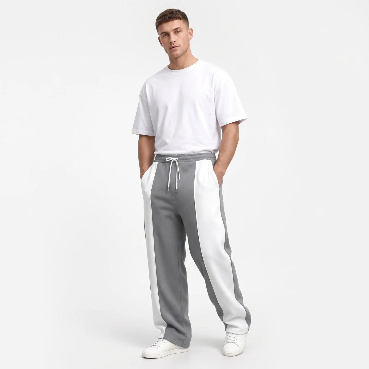 Studio shot of a model in grey sweatpants with white side panels and a white tee 14