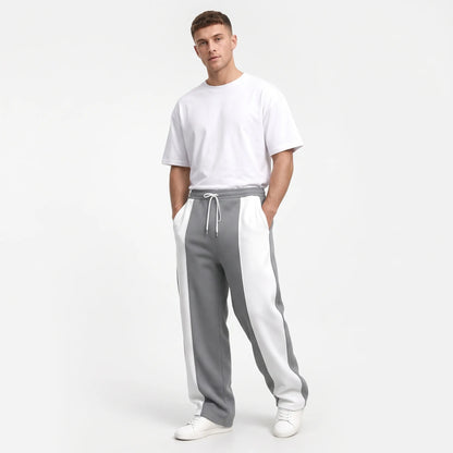 Studio shot of a model in grey sweatpants with white side panels and a white tee 14