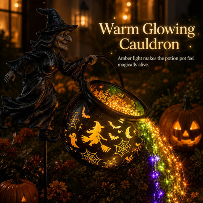 Close-up of the tilted cauldron glowing amber through its witch, bat, ghost and cobweb cut-outs, beside a carved pumpkin. 5