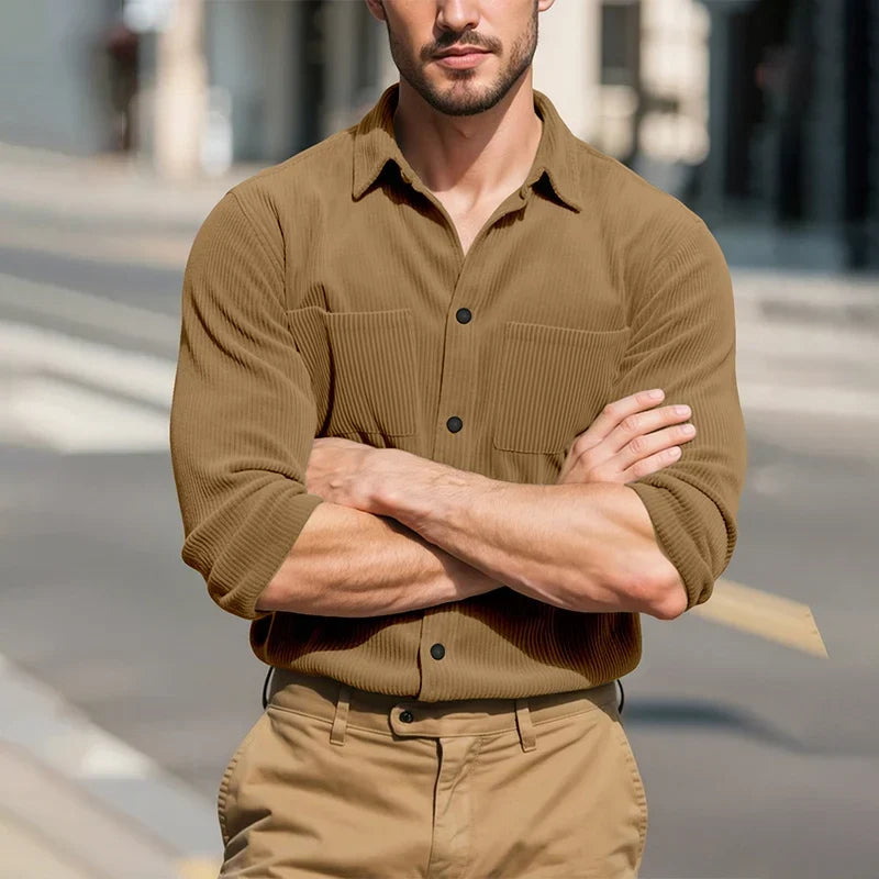 Model wearing the tan shirt with arms crossed on a sunlit street 15