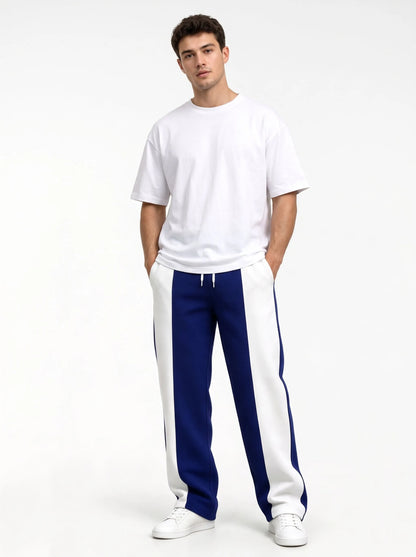 Studio shot of a model in deep blue sweatpants with white side panels and a white tee 15
