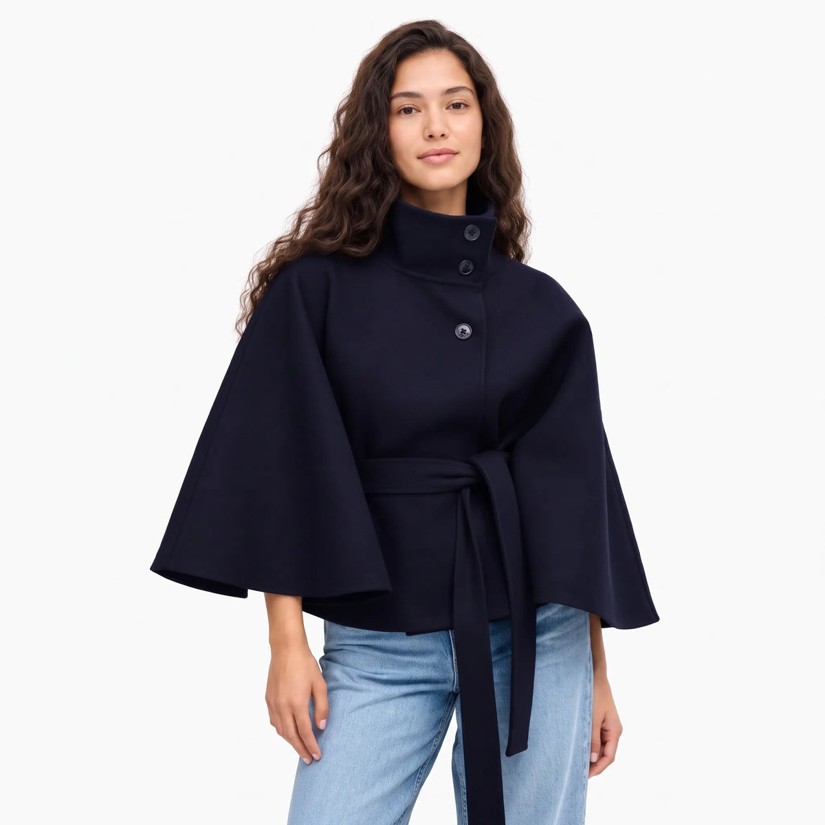 Studio shot of the navy cape jacket on a smiling model, wide sleeves and belt tied 15