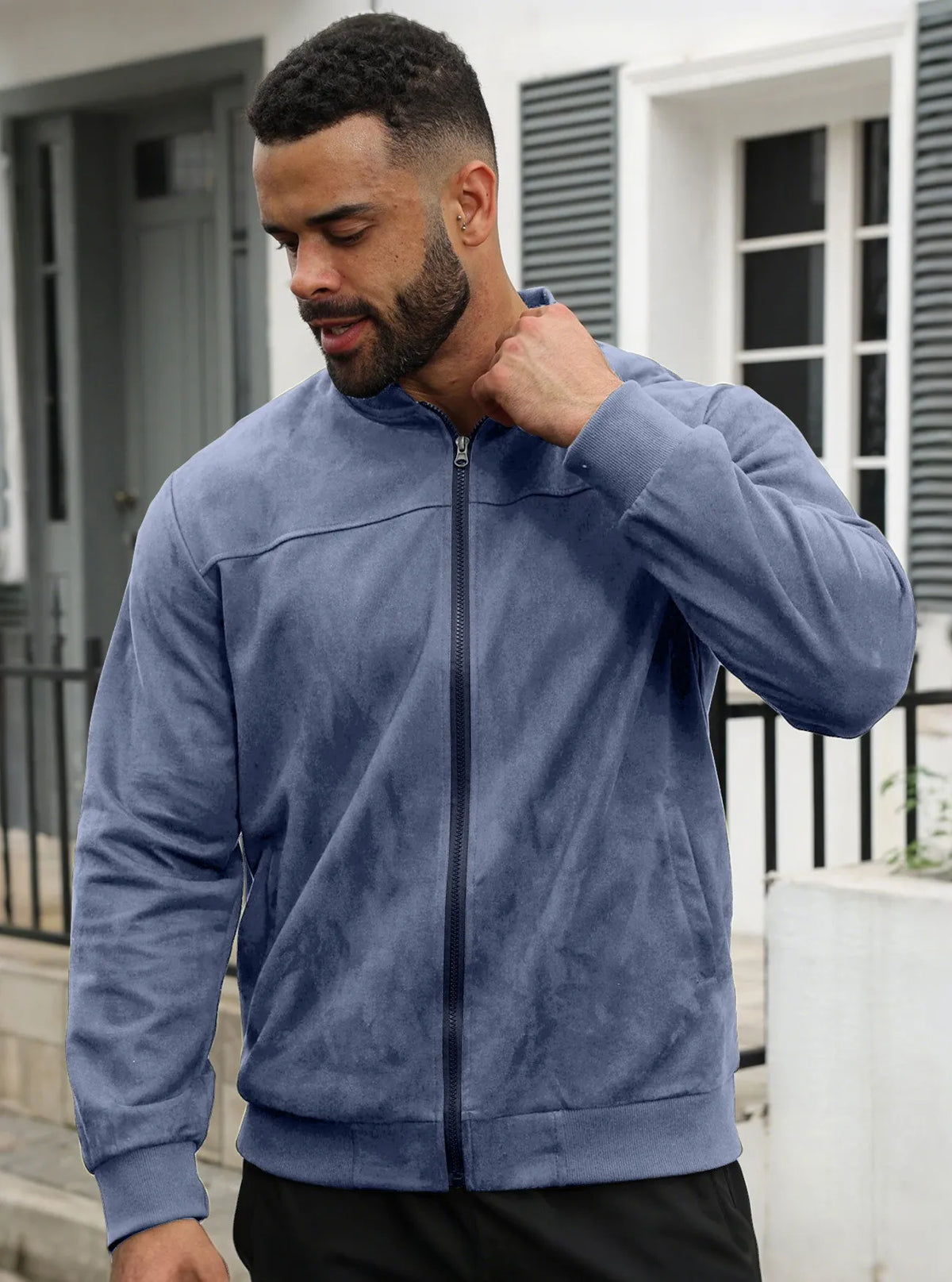 Bearded man outdoors in the blue zip jacket with hand raised to his collar 15