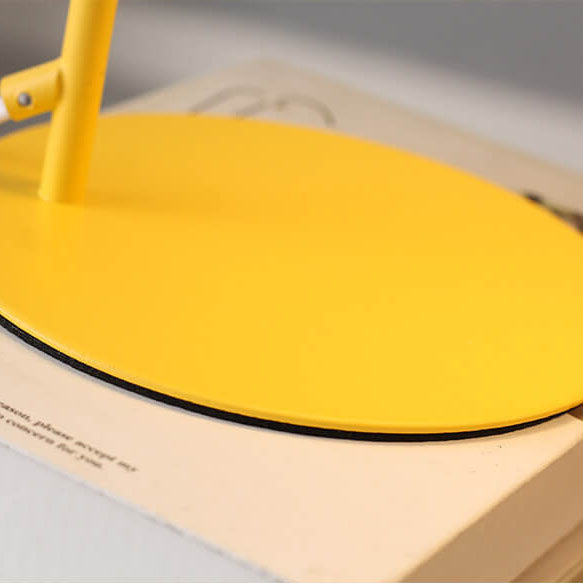 Close-up of the round flat yellow base with a dark rim, resting on a book. 4