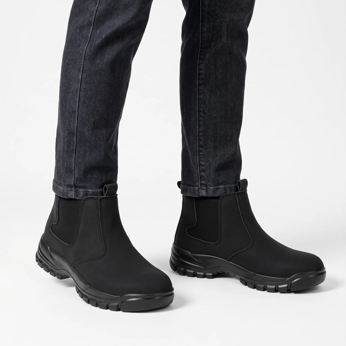 Black slip-on boots worn with charcoal jeans against a plain white studio background 15