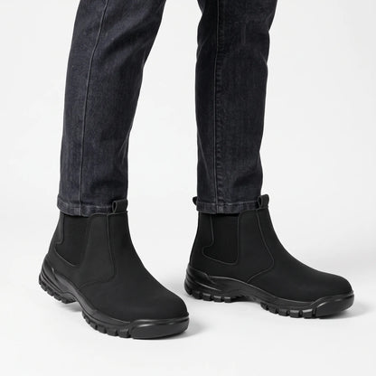 Black slip-on boots worn with charcoal jeans against a plain white studio background 15