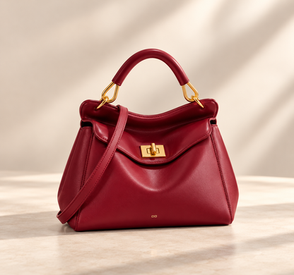 Smooth deep red version with gold turn-lock and crossbody strap, on a pale studio surface 5