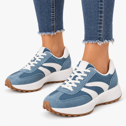 Blue suede and nylon trainers with curved white stripes and gum soles, worn with raw-hem jeans on white background 16