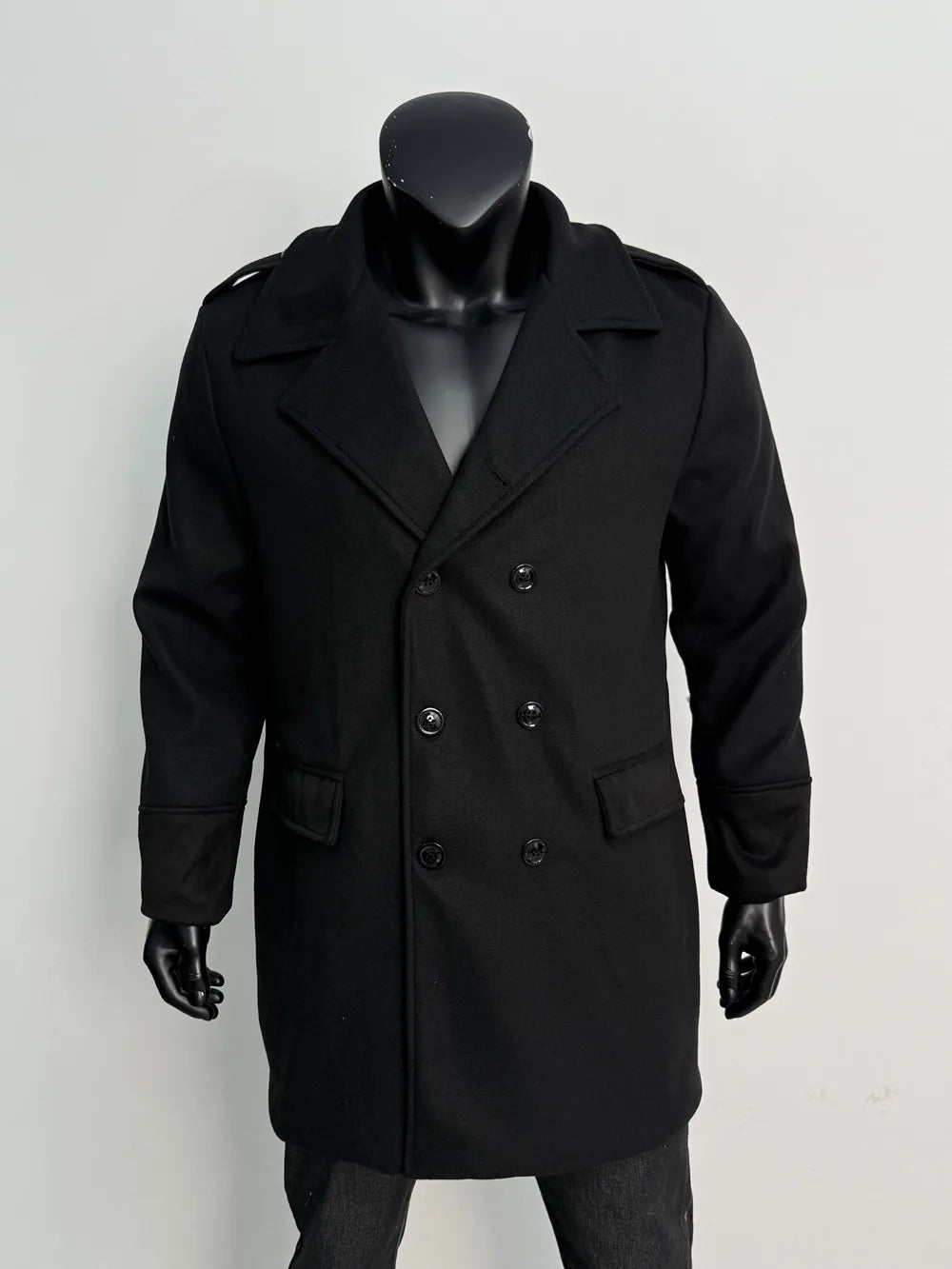 Black double-breasted overcoat on a mannequin, front view with six black buttons, notched lapels and flap pockets 16