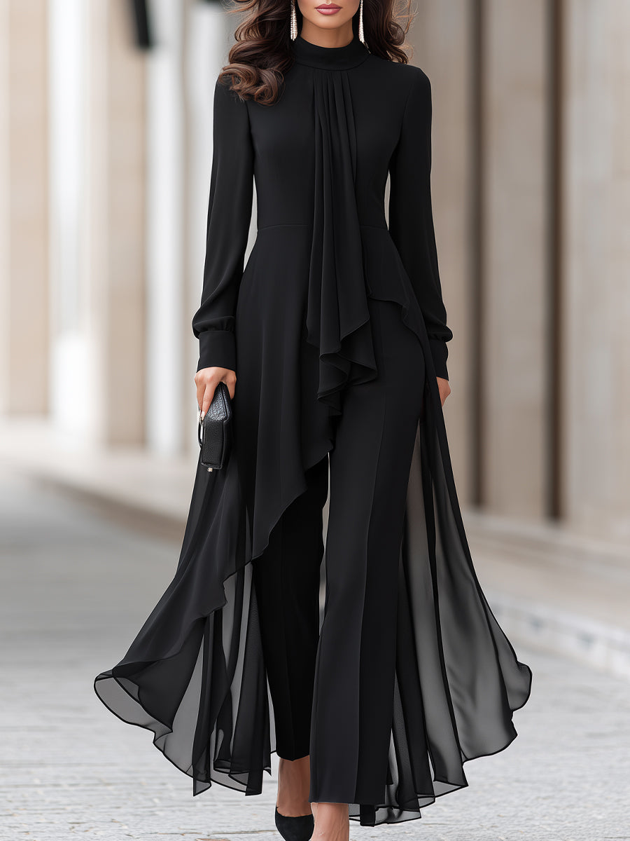 Model in a black high-neck tunic with long sleeves and sheer chiffon overlay, worn over wide-leg trousers, cropped at the knees. 1