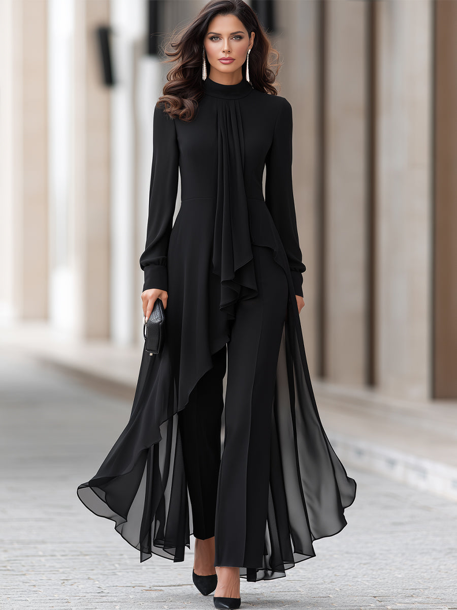 Full-length view of a model walking in the black chiffon tunic and wide-leg trousers, holding a small black clutch bag. 2