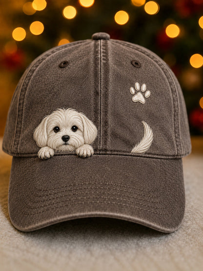 Front view of the cap in washed brown with a white puppy peeking over the peak, a paw print and tail. 6