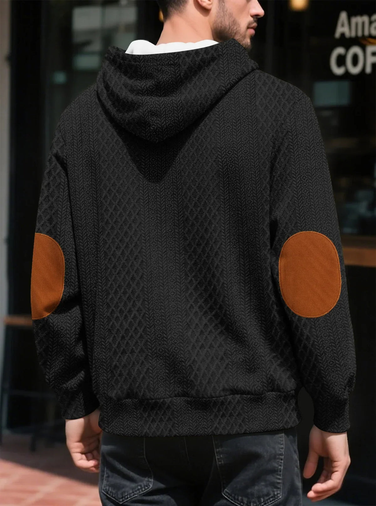 Back view of a black textured hoodie worn outdoors, showing large tan elbow patches and ribbed hem 17