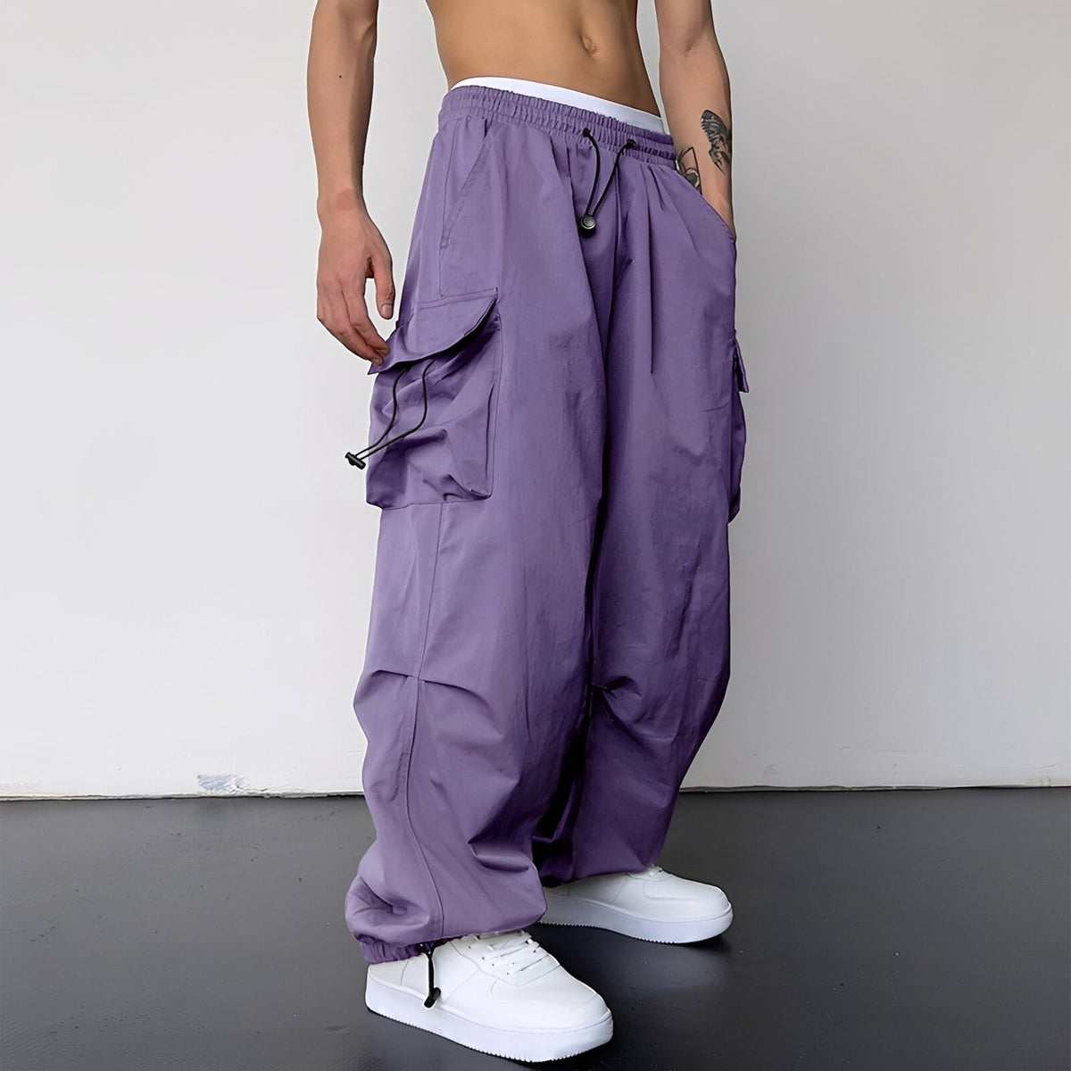 Model wears the baggy cargo trousers in lilac purple with white trainers, side view 5